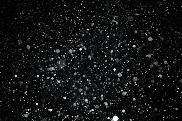Close up textura de fundo de flocos de neve durante uma queda de neve em um fundo preto — Fotografia de Stock