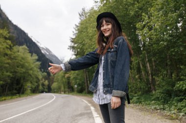 -Arabaya otostop dağlar arka plan üzerinde bekleyen genç kız