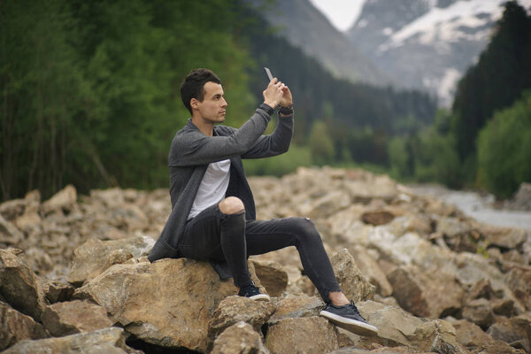 Молодой человек фотографирует на свой мобильный телефон
