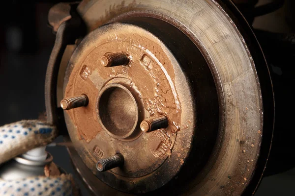 Car mechanic cleaning car wheel brake disk from rust corrosion at automobile repair service station — Stock Photo, Image