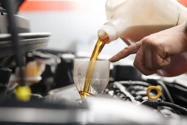 Mecânico de automóveis substituindo e derramando óleo fresco no motor na estação de serviço de reparação de manutenção — Fotografia de Stock