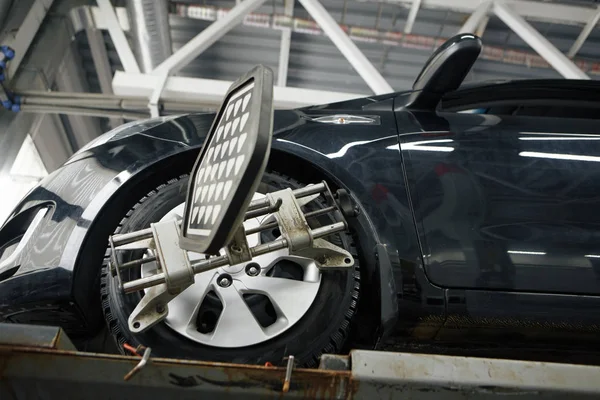 Mecânico de carro instalando sensor durante ajuste de suspensão e trabalho de alinhamento de roda de automóvel na estação de serviço de reparação — Fotografia de Stock