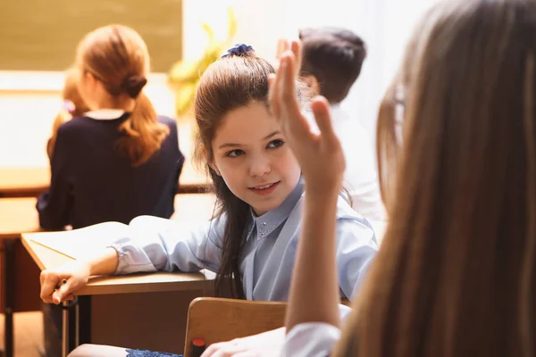 小学生在课上。它的小学学生。女孩勤奋地写,。在学校的课桌上有课本和学校配件 — 图库照片