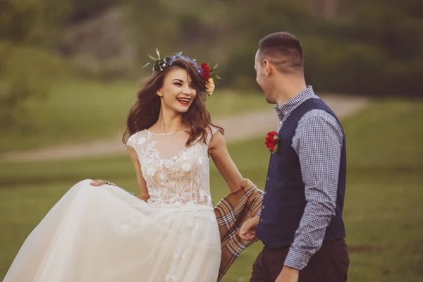 Boda. Novia y novio tomados de la mano y caminar en el campo verde —  Fotos de Stock