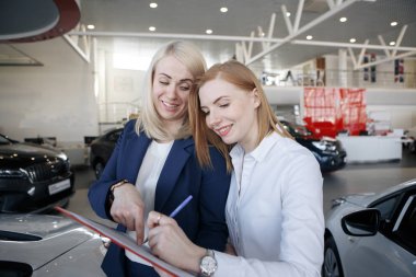 Woman signing a car insurance policy, the agent is pointing at the document clipart