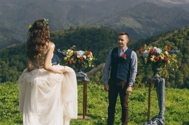 günbatımı, gelin ve damat iki sonra düğün kıyafetleri ile bir buket çiçek ve yeşillik alanın zemin karşı elinde olduğunu