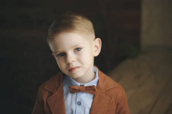 Bambino in età prescolare con gli occhi marroni in camicia a quadri e papillon rosso, distoglie lo sguardo, acconciatura alla moda , — Foto Stock