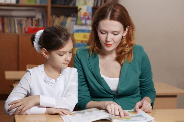 Feliz joven madre ayudando a su hija mientras estudia en casa — Foto de Stock