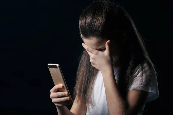 Jeden smutný teen držení mobilního telefonu bědovat, sedící na posteli v ložnici s temné světlo v pozadí — Stock fotografie
