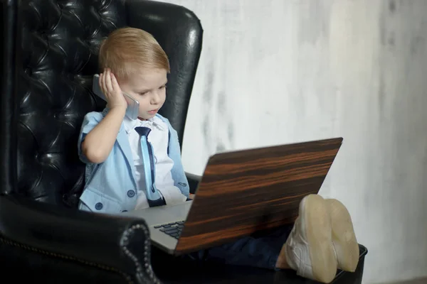 Jovem homem de negócios usando um laptop. Criança engraçada nos óculos. Retrato de moda de menino bonito no escritório — Fotografia de Stock