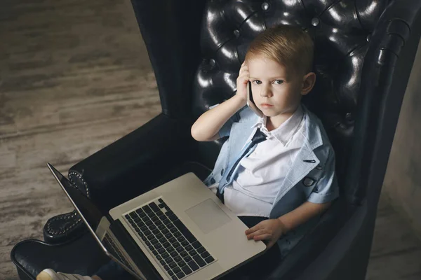 Slimme kleine peuter jongen met grote glazen drinken koffie tijdens het gebruik van haar laptop — Stockfoto