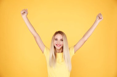 Attractive woman winner isolated in the yellow studio. clipart