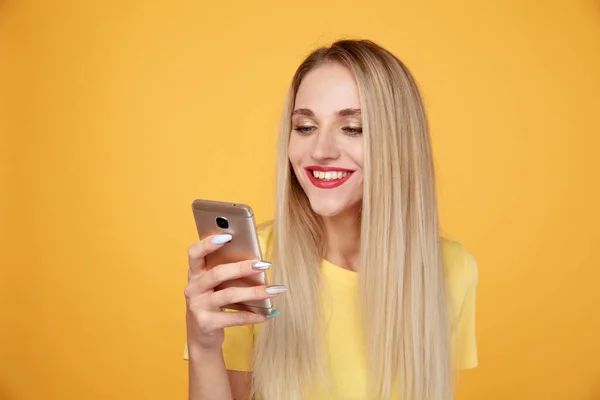 Happy dívka ve žlutém studiu s telefonem izolované. — Stock fotografie