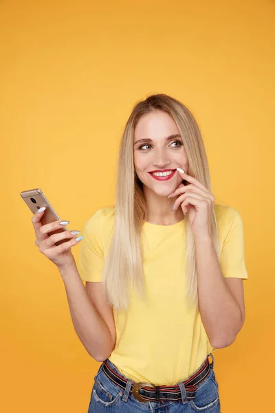 Happy dívka ve žlutém studiu s telefonem izolované. — Stock fotografie