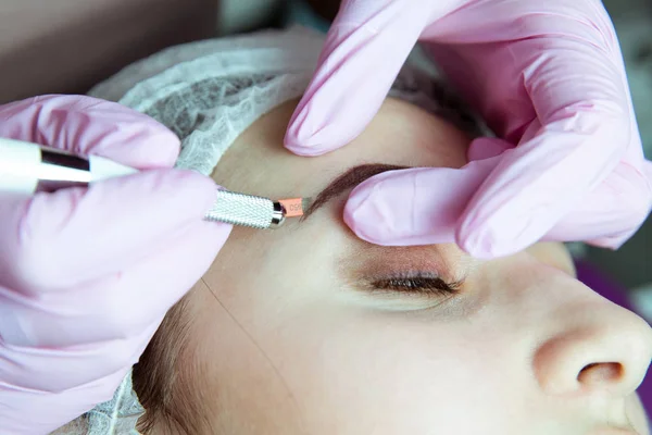 Maquiagem permanente para sobrancelhas. Testa de Microblading. Esteticista fazendo tatuagem de sobrancelha para rosto feminino. Menina bonita em uma beleza — Fotografia de Stock