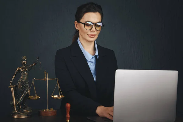 Lawyer office. Statue of Justice with scales and lawyer working on a laptop. Legal law, advice and justice .