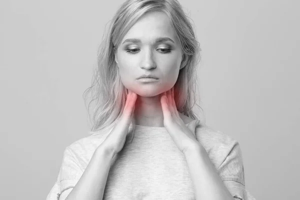 Mujer revisando la glándula tiroides sola. Primer plano de mujer en camiseta blanca tocando cuello con mancha roja. El trastorno tiroideo incluye bocio, hipertiroides, hipotiroides, tumor o cáncer. Asistencia sanitaria. — Foto de Stock