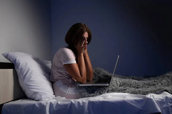 Mujer frustrada en tensión trabajando en una computadora portátil en casa sentada en la cama . —  Fotos de Stock