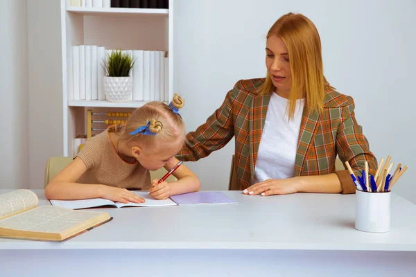 Mutter hilft kleiner Tochter bei Hausaufgaben Heimpädagogisches Konzept. — Stockfoto