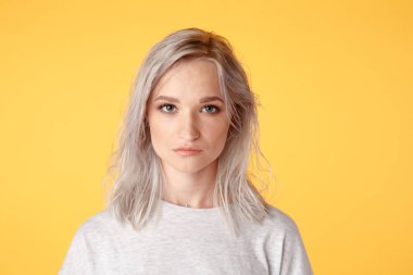 Closeup portrait of young blond female in the yellow studio.