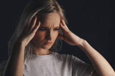 Blond female in stress with headache holding her hands on the head. Migraine concept.