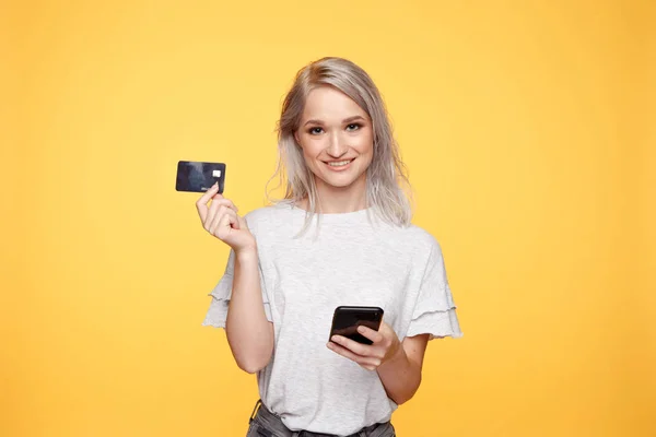 Uśmiechnięta dziewczyna z telefonem i kartą kredytową. Zakupy online koncepcja. — Zdjęcie stockowe