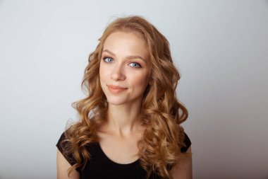 Beyaz stüdyoda poz veren hoş bir genç kadının portresi..