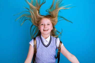 Sırt çantası izole bir okul elbisesi içinde sevimli gülümseyen kız.