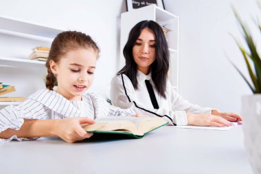 Anne Bebek kız ile oturan ve okumak için onu öğretmek.