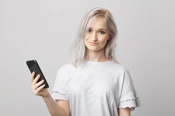 Šťastná blondýnka ve studiu drží telefon. — Stock fotografie