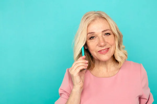 Mulher adulto falando telefone no estúdio azul . — Fotografia de Stock
