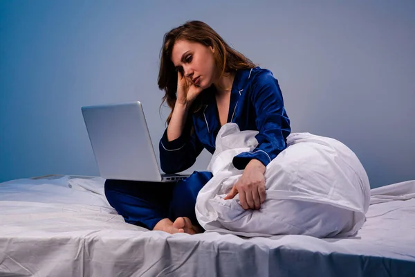 Imagen de mujer cansada en casa sentada con computadora en la cama por la noche . —  Fotos de Stock