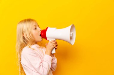 Çocuk megafonla bağırıyor. İletişim konsepti. Metnin için kopyalama alanı olarak sarı arkaplan