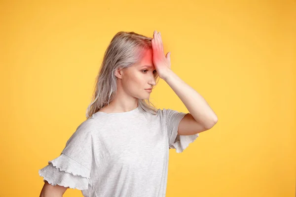 Blonde junge Frau verspürt Kopfschmerzen im Studio. — Stockfoto