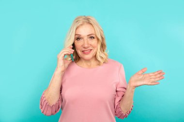 Tatlı sürpriz orta yaşlı kadın konuşan mavi telefon izole edilmiş..