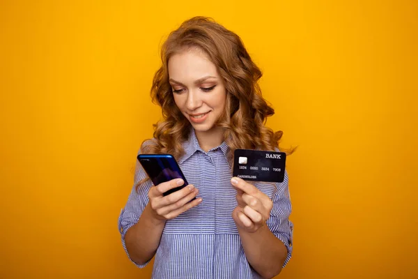 Zakupy przez internet. Szczęśliwa kobieta trzyma telefon i kartę kredytową w izolacji. — Zdjęcie stockowe