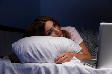 Yatakta dizüstü bilgisayarlı uyuyan genç bir internet bağımlısı..