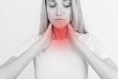 Tiroid bezini tek başına kontrol eden bir kadın. Beyaz tişörtlü bir kadının kırmızı noktalı boynuna dokunuşunu yakından çek. Tiroid bozukluğu guatr, hipertiroid, hipotiroid, tümör ya da kanseri içerir. Sağlık hizmetleri.