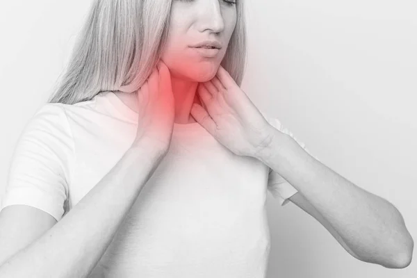 Mujer revisando la glándula tiroides sola. Primer plano de mujer en camiseta blanca tocando cuello con mancha roja. El trastorno tiroideo incluye bocio, hipertiroides, hipotiroides, tumor o cáncer. Asistencia sanitaria. — Foto de Stock