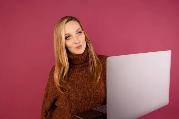 Happy woman with laptop isolated in the pink studio.