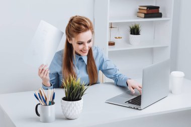 Fotoğraf gülümseyen iş kadını ofiste oturma ve çalışma. Telefon kullanma office. Office çalışan holding belgeleri.