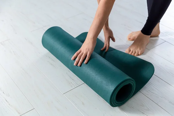 Closeup picture of yoga green mat. Woman is getting ready for exercises indoor. — Stok fotoğraf