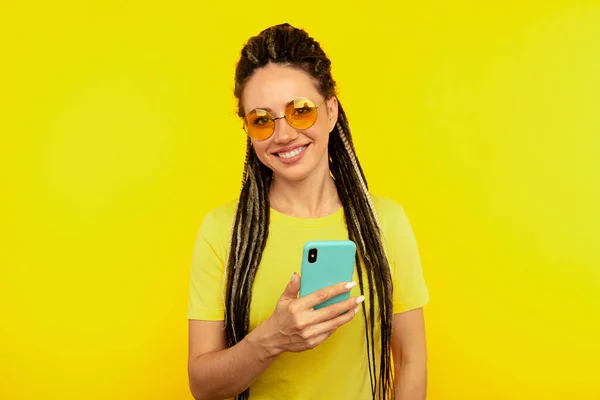 Glücklich lächelnde Frau mit hellem Handy im gelben Studio. — Stockfoto