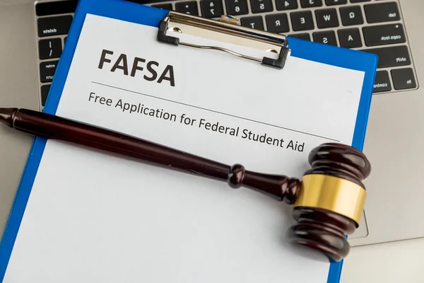 Fafsa. Student aid concept. Application form of document on the table with wooden hammer isolated.