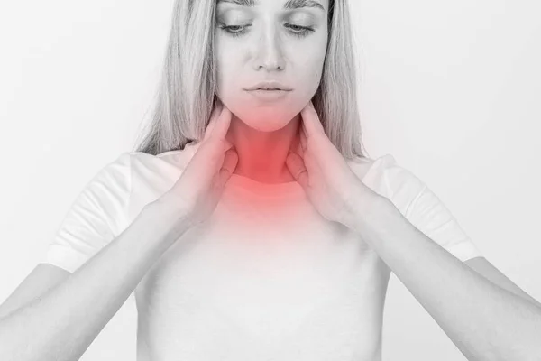 Mujer revisando la glándula tiroides sola. Primer plano de mujer en camiseta blanca tocando cuello con mancha roja. El trastorno tiroideo incluye bocio, hipertiroides, hipotiroides, tumor o cáncer. Asistencia sanitaria. — Foto de Stock