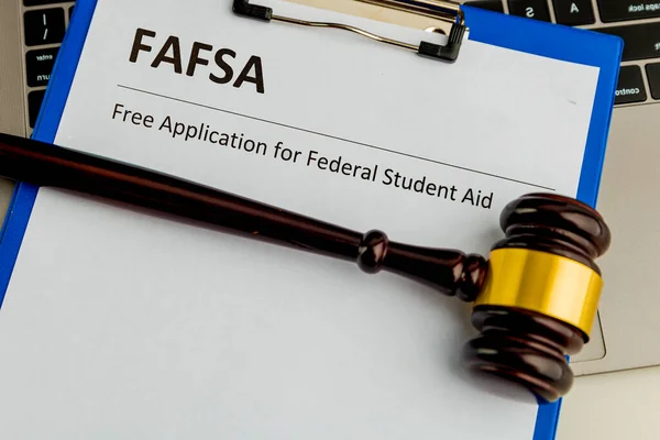 Fafsa. Student aid concept. Application form of document on the table with wooden hammer isolated.