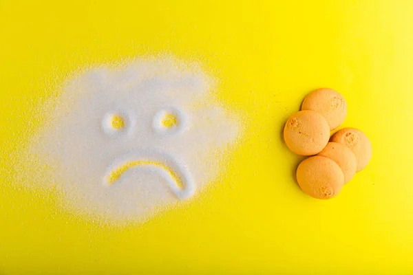 Сумне цукрове обличчя дивиться на солодке печиво на жовтому тлі . — стокове фото