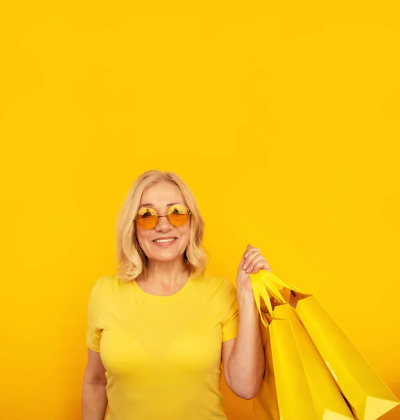 Lachende positieve vrouw in een zonnebril met veel boodschappentassen. — Stockfoto