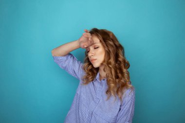 Yorgun genç bayan gözlerini kapattı ve elini mavi stüdyoda kafasının üstüne koydu..