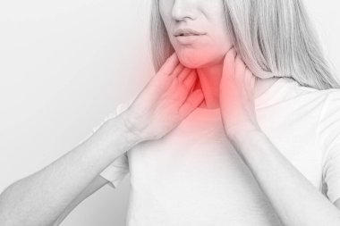 Tiroid bezini tek başına kontrol eden bir kadın. Beyaz tişörtlü bir kadının kırmızı noktalı boynuna dokunuşunu yakından çek. Tiroid bozukluğu guatr, hipertiroid, hipotiroid, tümör ya da kanseri içerir. Sağlık hizmetleri.